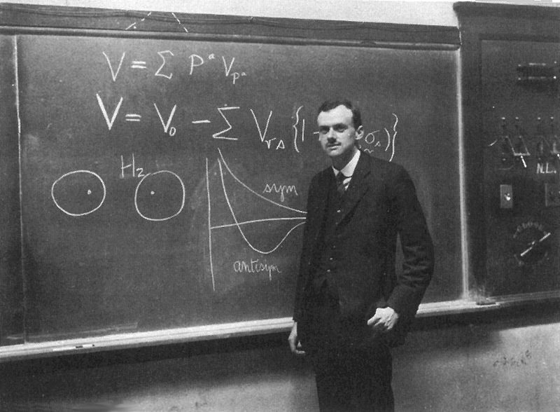 Paul Dirac standing in front of a blackboard